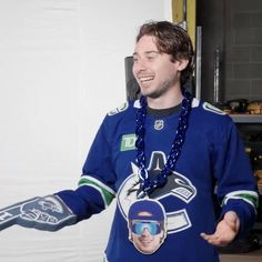 a man in a hockey jersey is holding his hands out to the side and smiling