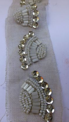 three pieces of white beaded fabric with gold and silver accents on top of each other