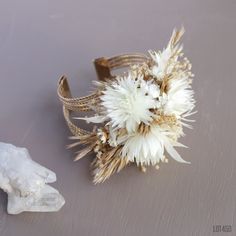 a white flower sitting on top of a table next to a small piece of rock