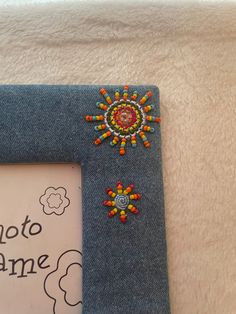 a photo frame with beaded decorations on the front and back of it, sitting on a white surface