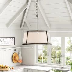 a kitchen with white cabinets and an island light hanging from it's center beam