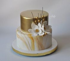 a white and gold marble cake with flowers on the top is ready to be eaten