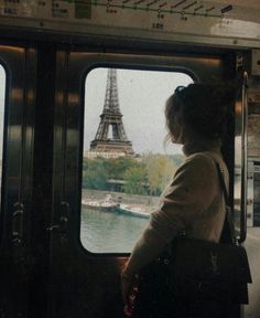 a woman looks out the window at the eiffel tower