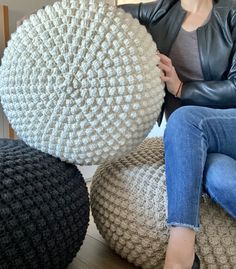 a woman sitting on top of a couch holding a large white knitted ball in front of her face