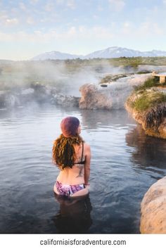 a woman sitting in the middle of a body of water with steam rising from her back