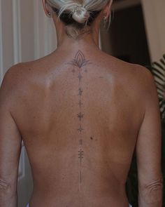 the back of a woman's neck with tattoos on her upper and lower back