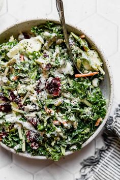 a bowl filled with salad on top of a white tiled counter next to a fork