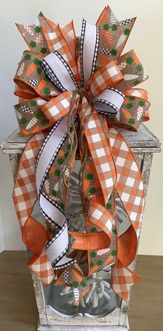 a large orange and white bow on top of a wooden box with ribbon around it