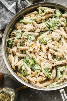 a pan filled with pasta and broccoli on top of a table next to utensils