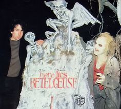 two people standing next to a fake skeleton