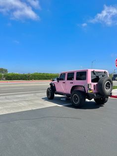 a pink jeep is parked on the side of the road in front of a stop sign