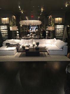 a living room filled with white couches and lamps on top of it's tables