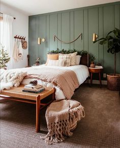 a bed room with a neatly made bed next to a table and two plants on the wall