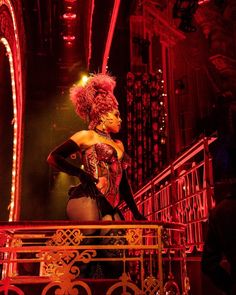 a woman in a corset standing on top of a stair case at night