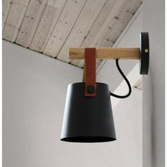 a black and brown lamp hanging from a wooden beam in a room with white walls