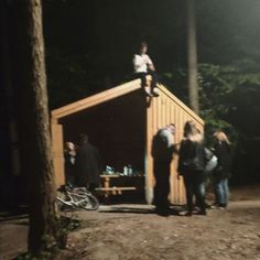 a group of people standing on top of a wooden structure in the woods at night