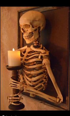 a skeleton holding a lit candle in front of a mirror with the caption's name on it