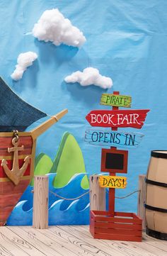 an image of a pirate book fair sign in front of a blue background with clouds