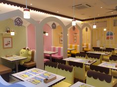 the interior of a restaurant with yellow and pink chairs, tables and booths in it