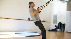 a man holding onto a rope while standing on top of a wooden floor