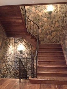 an empty room with stone walls and wooden floors, stairs leading up to the second floor