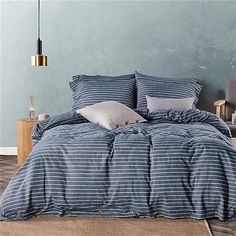 a bed with blue and white striped comforter next to a wooden nightstand in a bedroom