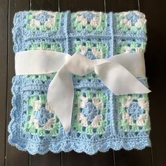 a crocheted blanket with a white bow on the front and blue squares in the back