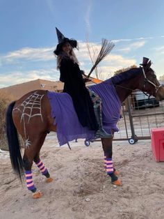 a woman dressed up as a witch riding a horse