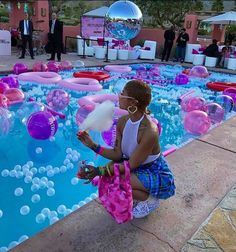 a woman sitting in front of a pool filled with balloons