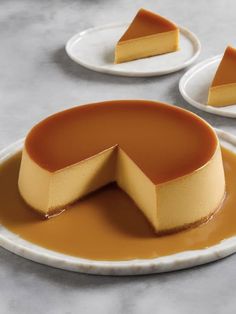 a piece of cheesecake on a plate with caramel sauce and two plates behind it