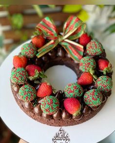 a chocolate cake decorated with strawberries and green sprinkles on a white plate