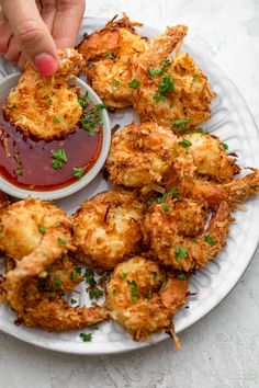 a person dipping sauce on some fried food with ketchup in a white plate