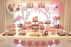 the dessert table is decorated with pink flowers and umbrellas