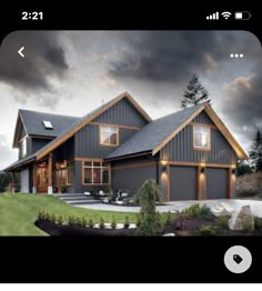 a large gray house sitting on top of a lush green field next to a forest