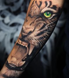 a tiger with its mouth open and green eyes on his arm, showing it's teeth