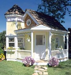 a small yellow house sitting on top of a lush green field