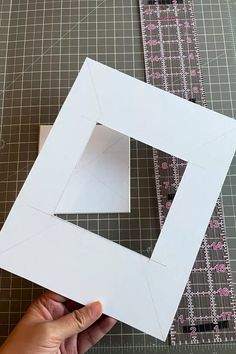 someone is cutting out the shape of a square with a ruler on top of it