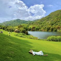 a person laying on the grass in front of a lake