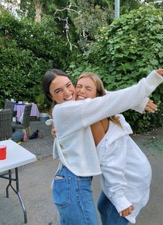 two women hugging each other in front of a table with food and drinks on it