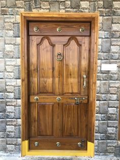 a wooden door with brass handles on a brick wall in front of a stone building