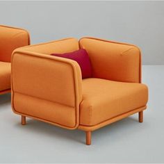 two orange chairs with red pillows on them