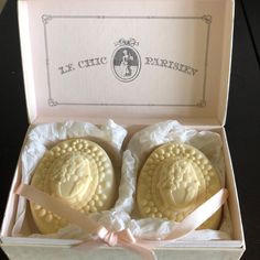 two white cookies in a box with pink ribbon