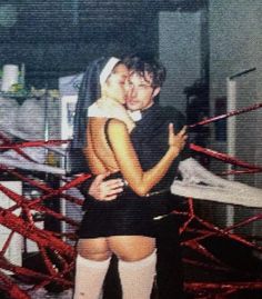 a man and woman hugging each other in the middle of a room with red ropes