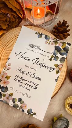 the wedding stationery is displayed next to some pine cones and candles