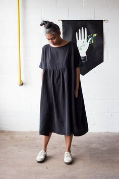 Part of our basics collection. Effortless addition to the warm-weather wardrobe. Casual yet statement-making. Oversized drapy black smock dress with gathered waist, boat neckline, 3/4 dolman sleeves and in-seem pockets. This oversized midi dress is made from a beautiful thick eco friendly lyocell and features super flattering half sleeves.>> Size chartOne Size Fits All (58in wide at bust). Please note an alterated version at sleeves can be made to fit up to 4X.Length : 44in.Content: 100% L Black Smock Dress, Tencel Dress, Long Midi Dress, Comfy Dresses, Black Long Sleeve Dress, Long Black Dress, Modern Outfits, Classic Dress, Smock Dress