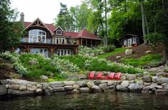 a large house sitting on top of a lush green hillside next to a body of water