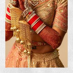 a woman in a gold and red bridal outfit with her hands on her hip