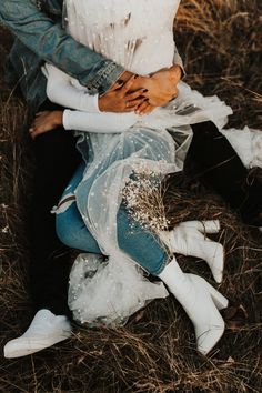 a man and woman sitting on the ground in front of each other with their arms around each other