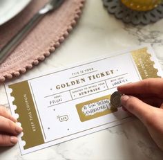 a person is holding a golden ticket on a table