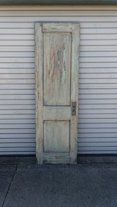 an old wooden door sitting in front of a white garage door on the side of a building